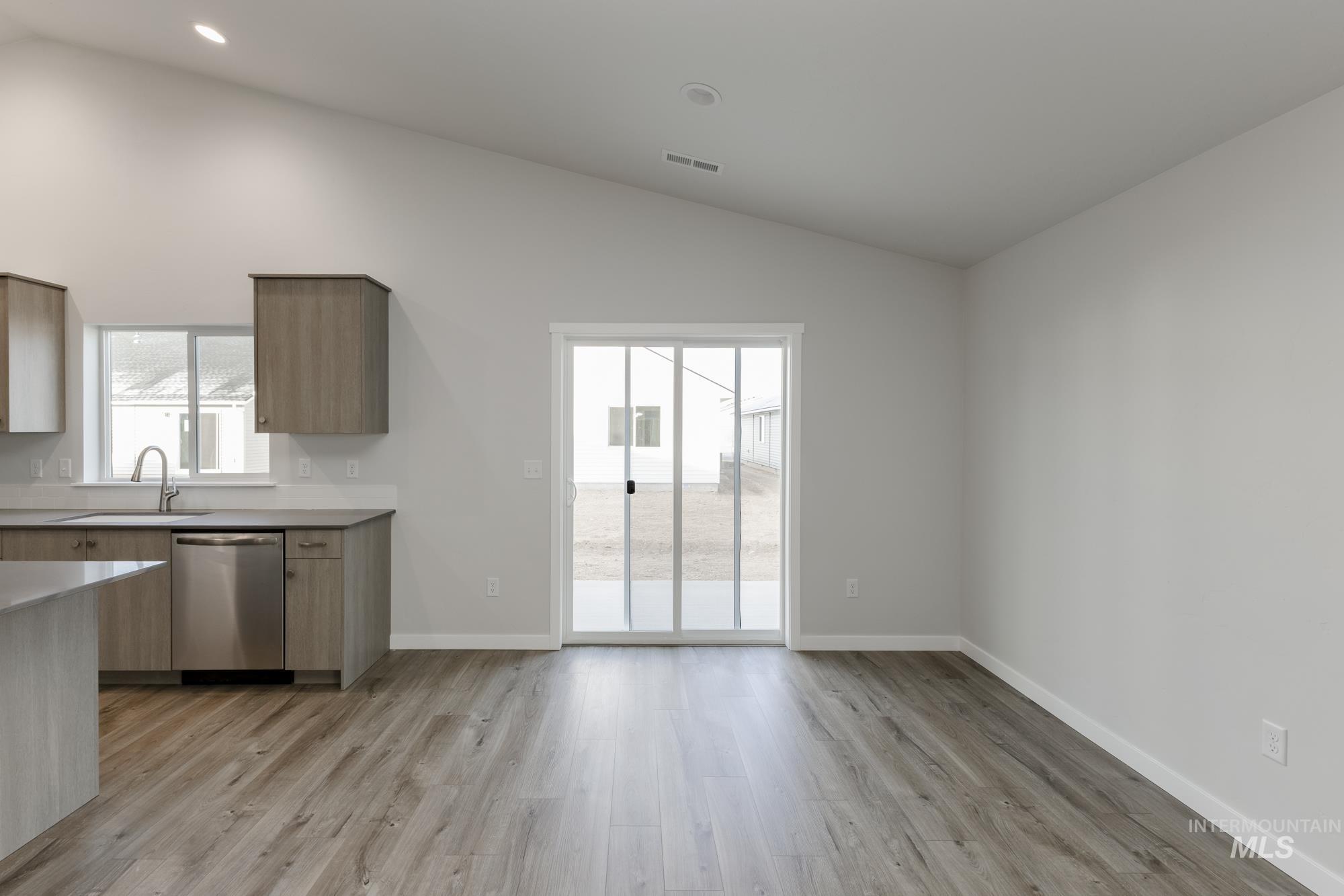Kitchen featuring lofted ceiling, light wood-style flooring, stainless steel dishwasher, and modern cabinets