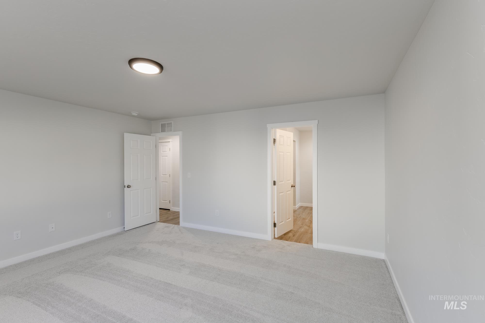 Unfurnished bedroom with light carpet and baseboards