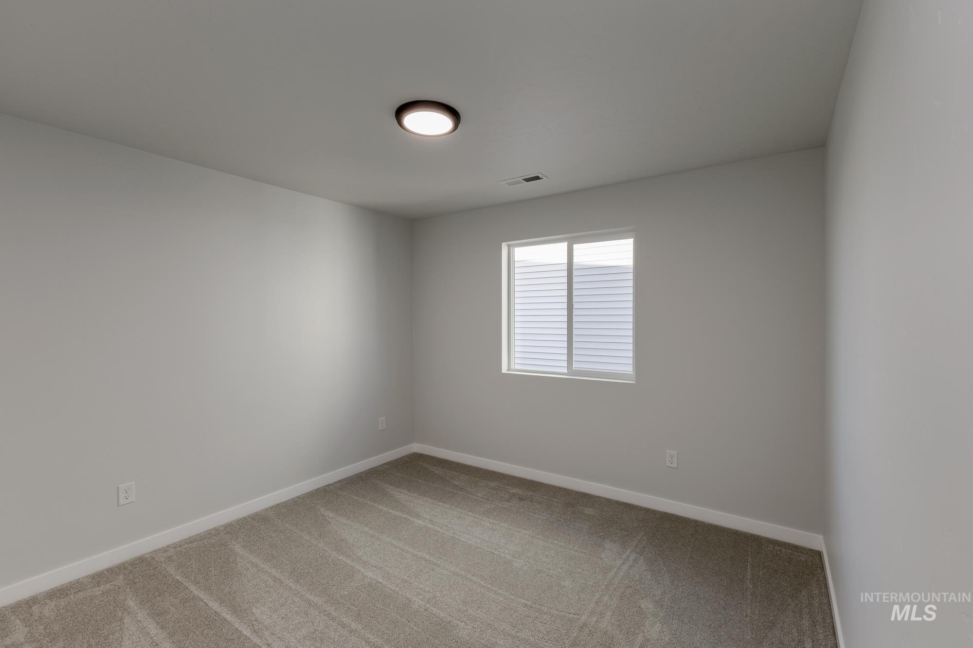 Empty room featuring baseboards and light carpet
