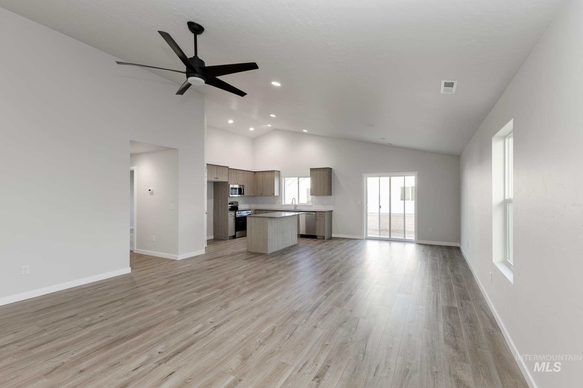 Unfurnished living room featuring vaulted ceiling, light wood-style floors, ceiling fan, and recessed lighting