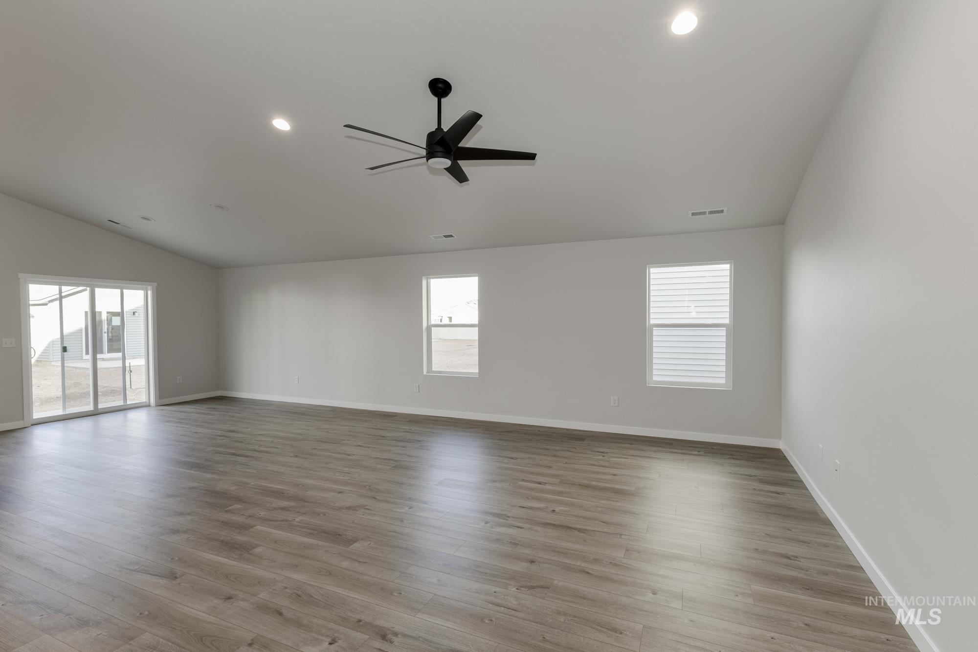 Empty room with lofted ceiling, light wood-type flooring, plenty of natural light, ceiling fan, and recessed lighting