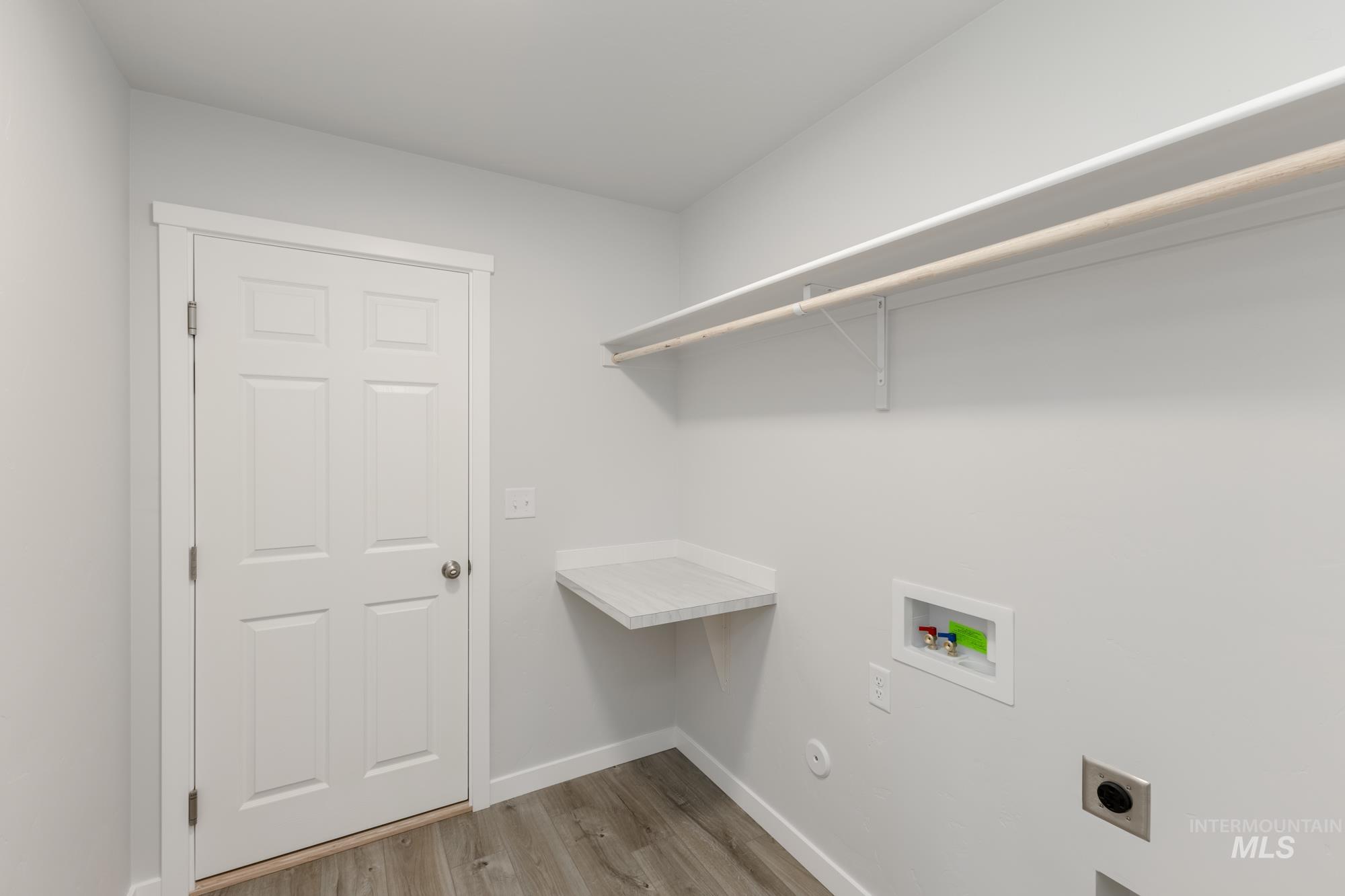 Washroom with hookup for a washing machine, electric dryer hookup, light wood finished floors, and hookup for a gas dryer