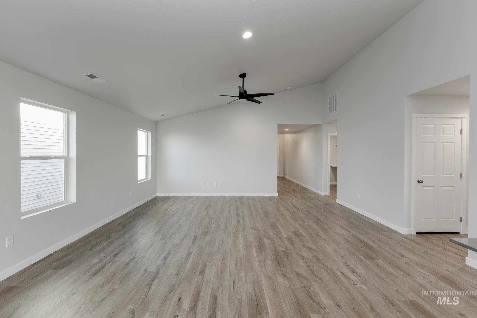 Unfurnished living room featuring vaulted ceiling, light wood-style flooring, ceiling fan, and recessed lighting