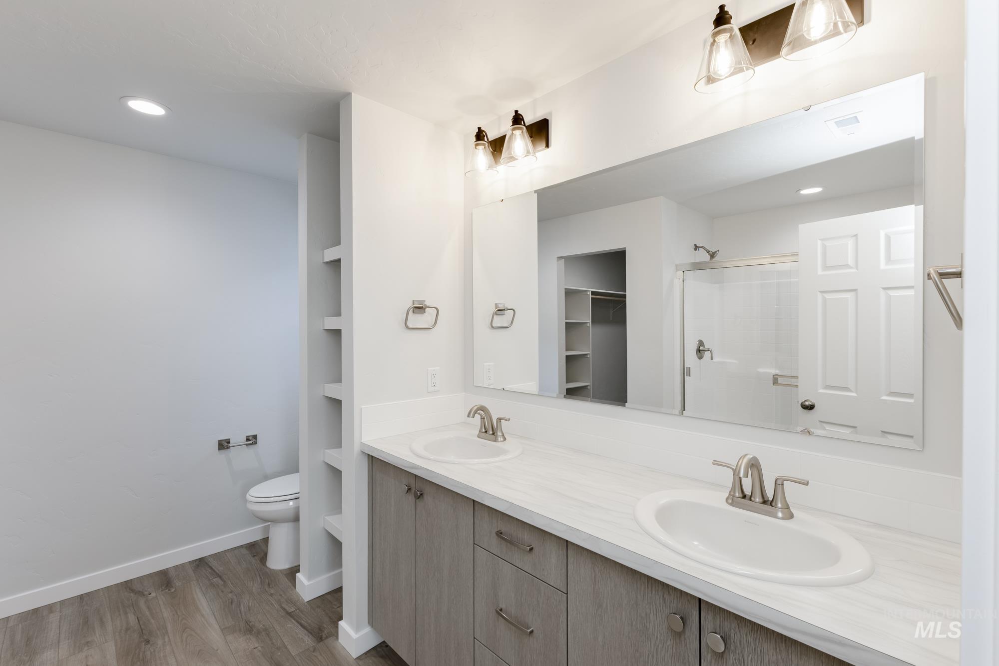Bathroom with a stall shower, double vanity, recessed lighting, a walk in closet, and light wood finished floors
