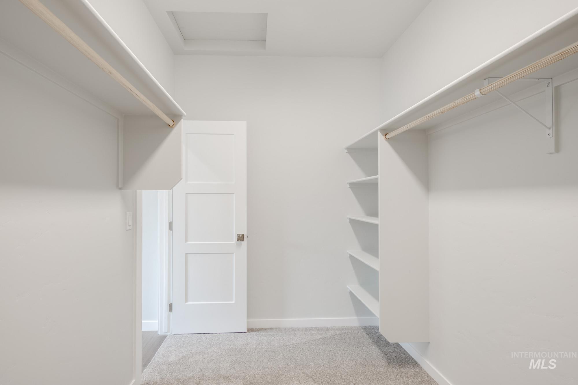 Spacious closet with carpet flooring and attic access
