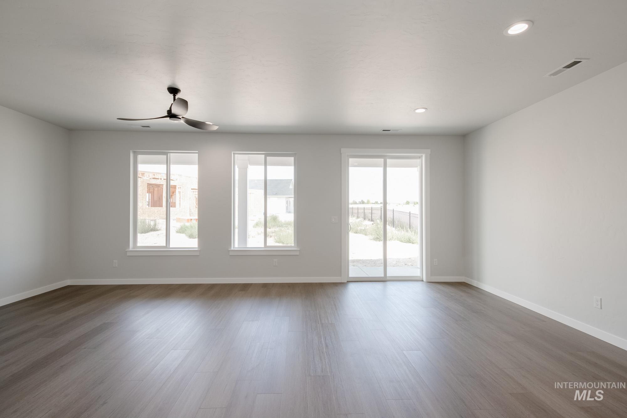 Unfurnished room with healthy amount of natural light, dark wood-style flooring, a ceiling fan, and recessed lighting