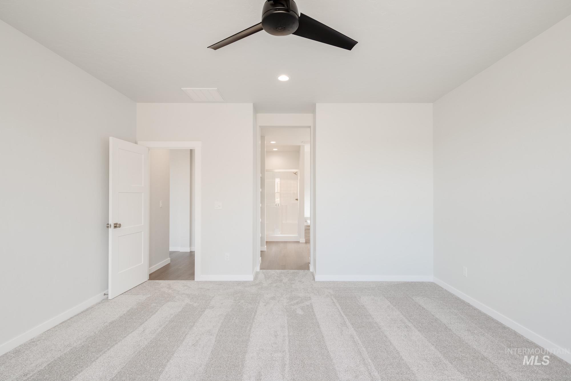 Unfurnished bedroom featuring light carpet, recessed lighting, ensuite bath, and a ceiling fan
