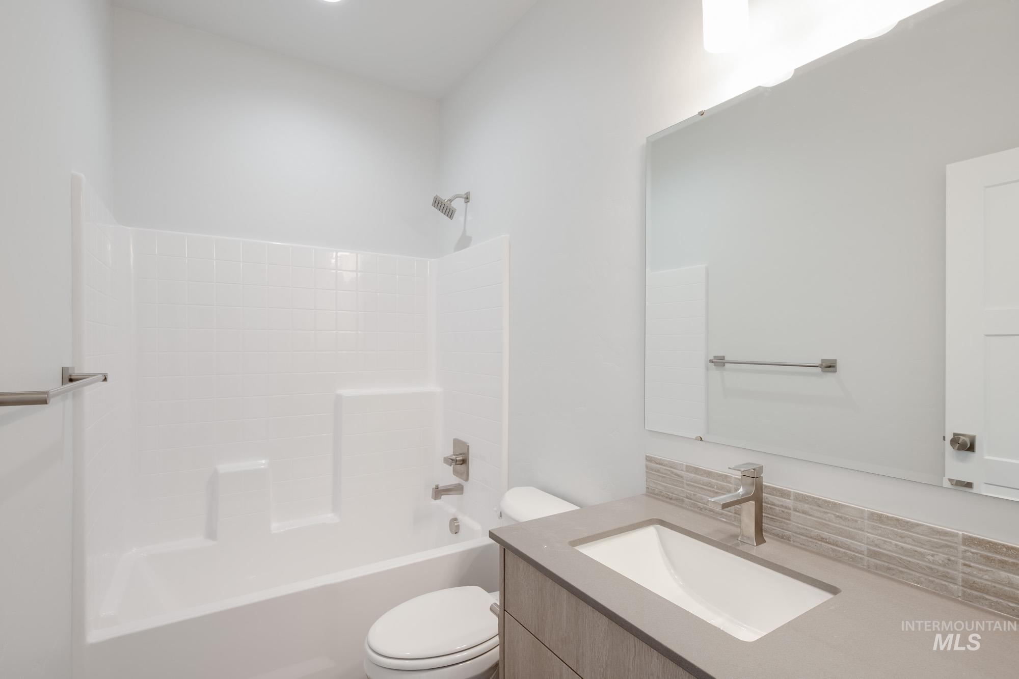 Bathroom featuring vanity, bathtub / shower combination, and tasteful backsplash