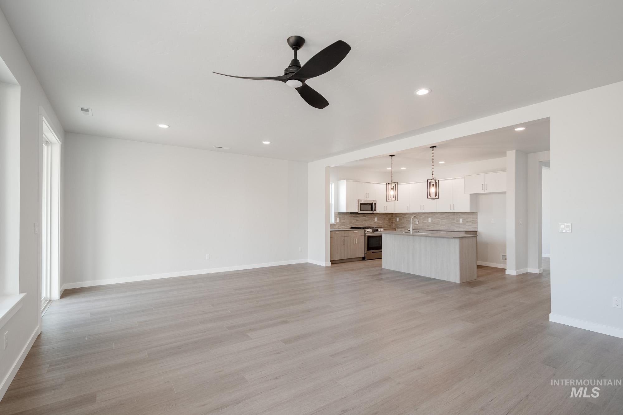 Unfurnished living room with light wood-type flooring, ceiling fan, and recessed lighting