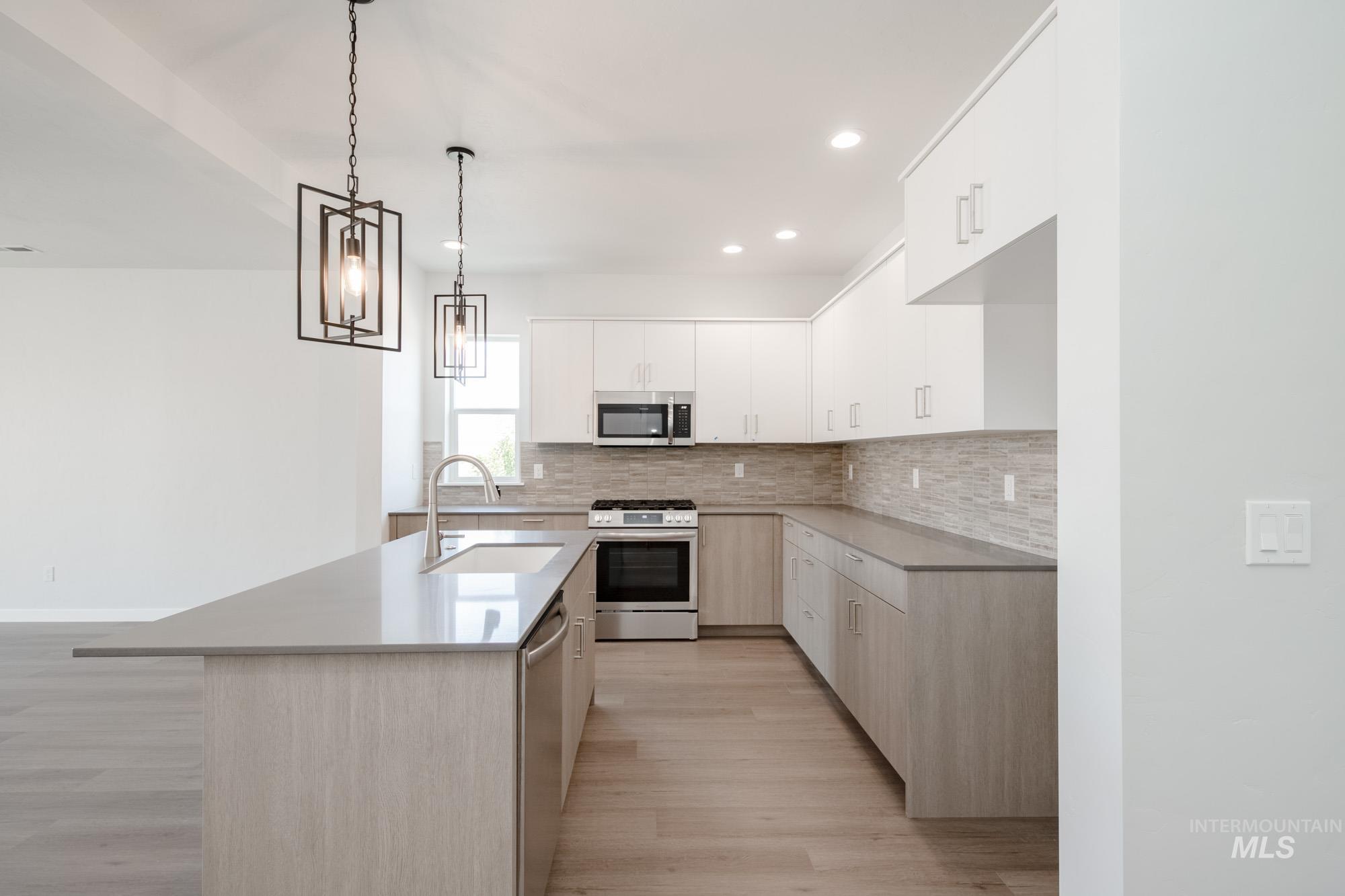 Kitchen with appliances with stainless steel finishes, light wood-style flooring, tasteful backsplash, modern cabinets, and recessed lighting