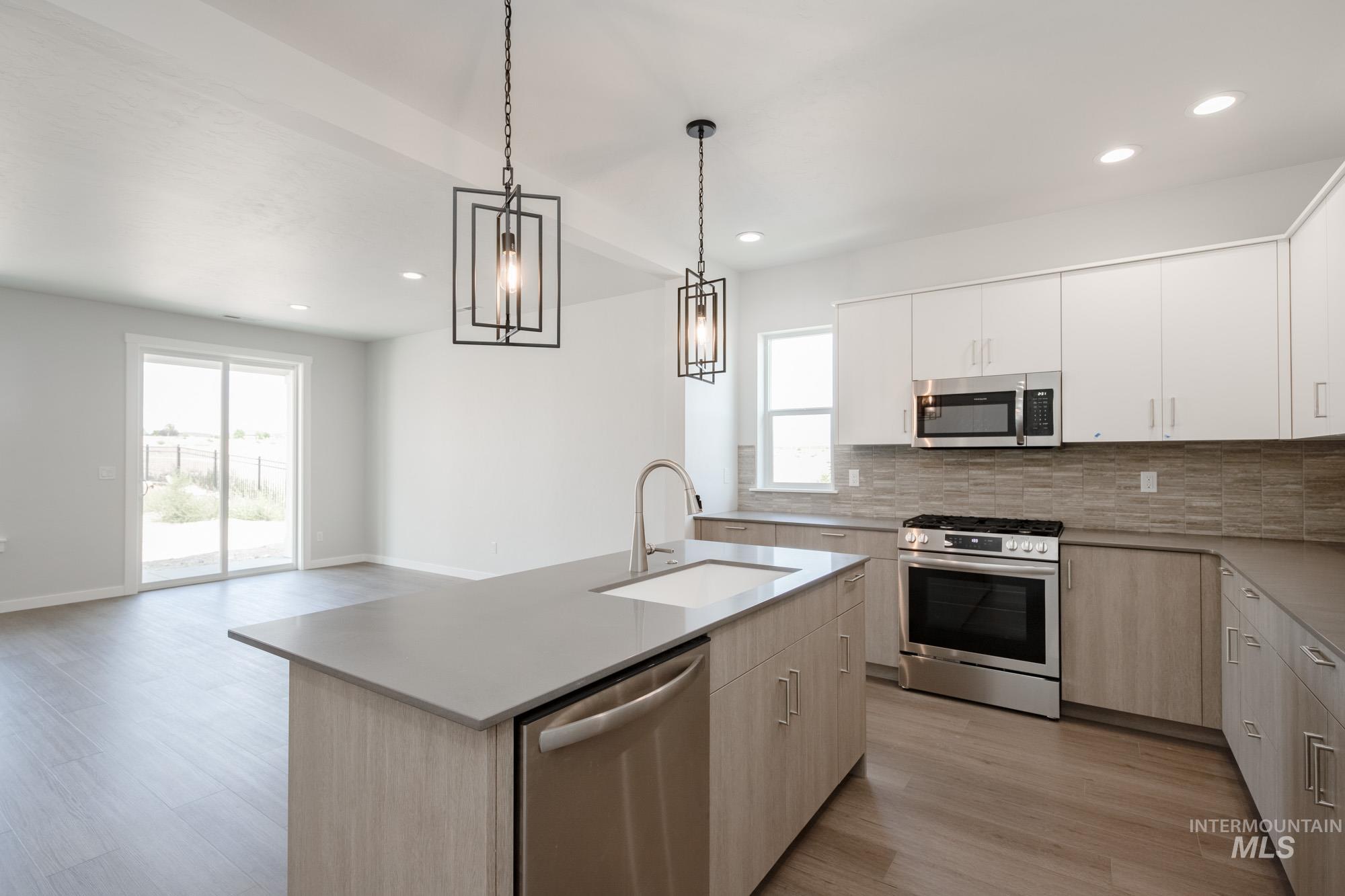 Kitchen featuring stainless steel appliances, light wood-type flooring, backsplash, light countertops, and recessed lighting