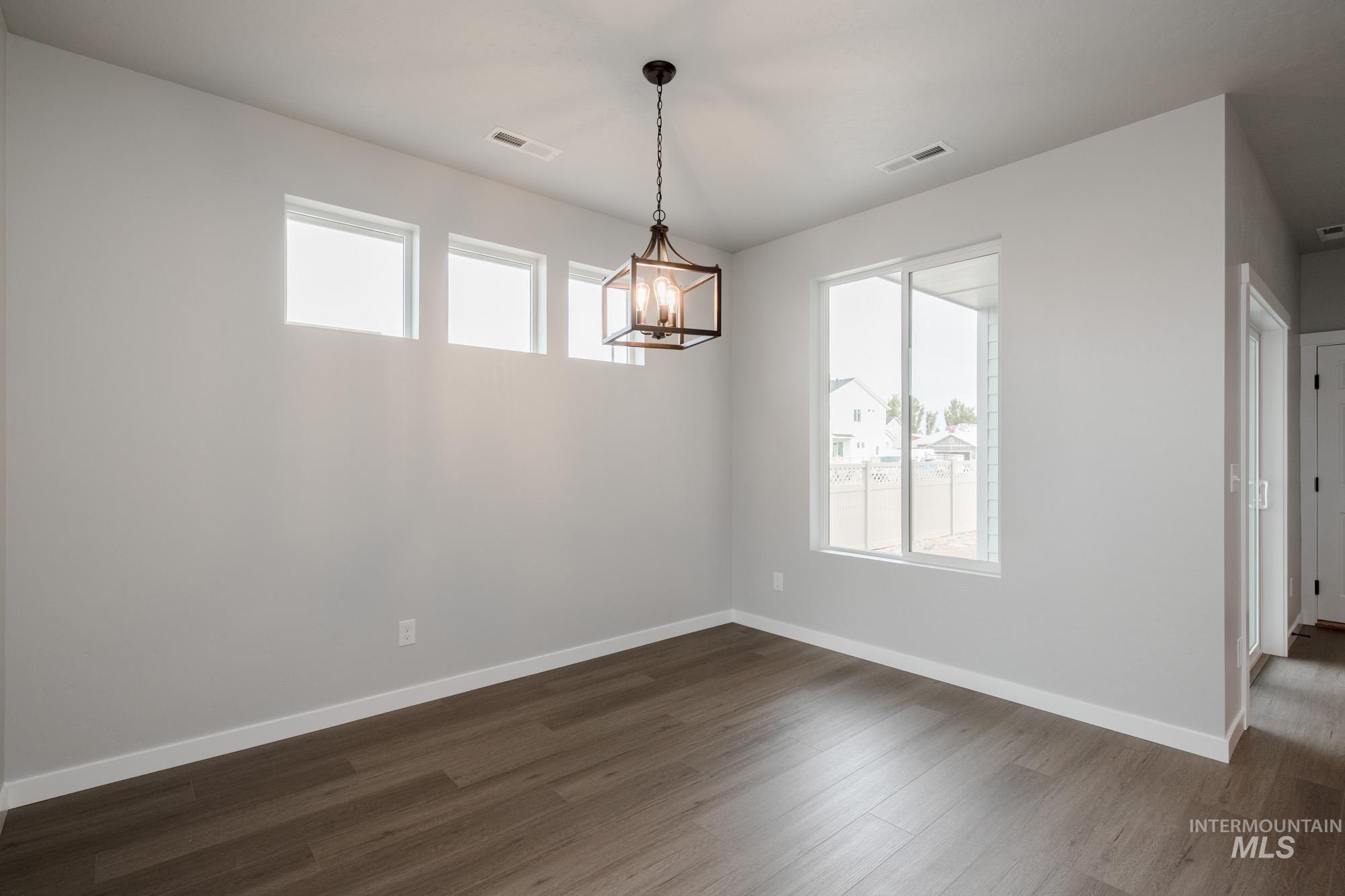 Unfurnished dining area with dark wood-type flooring and a chandelier