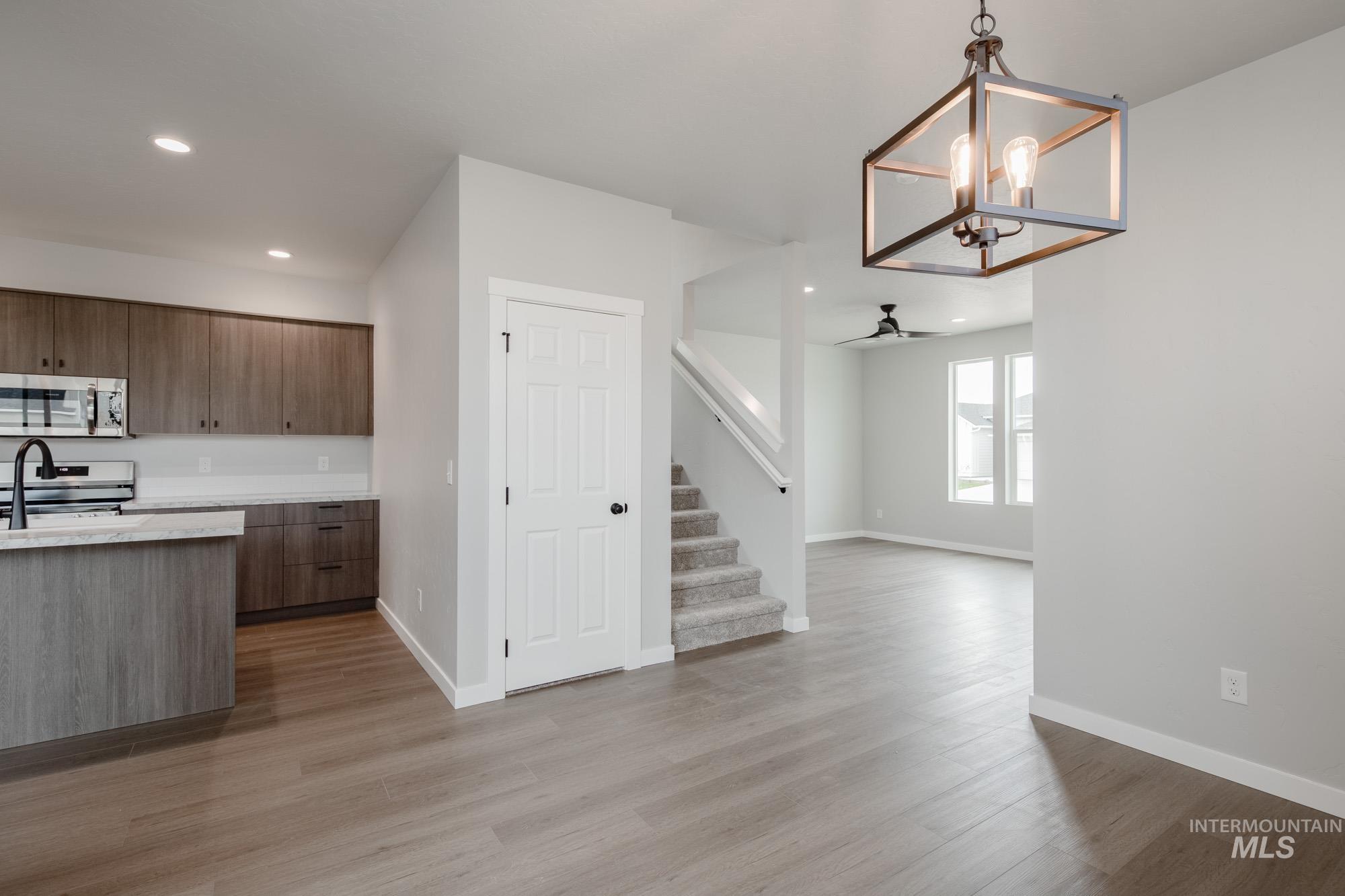Kitchen with modern cabinets, decorative light fixtures, appliances with stainless steel finishes, a chandelier, and light wood-style floors