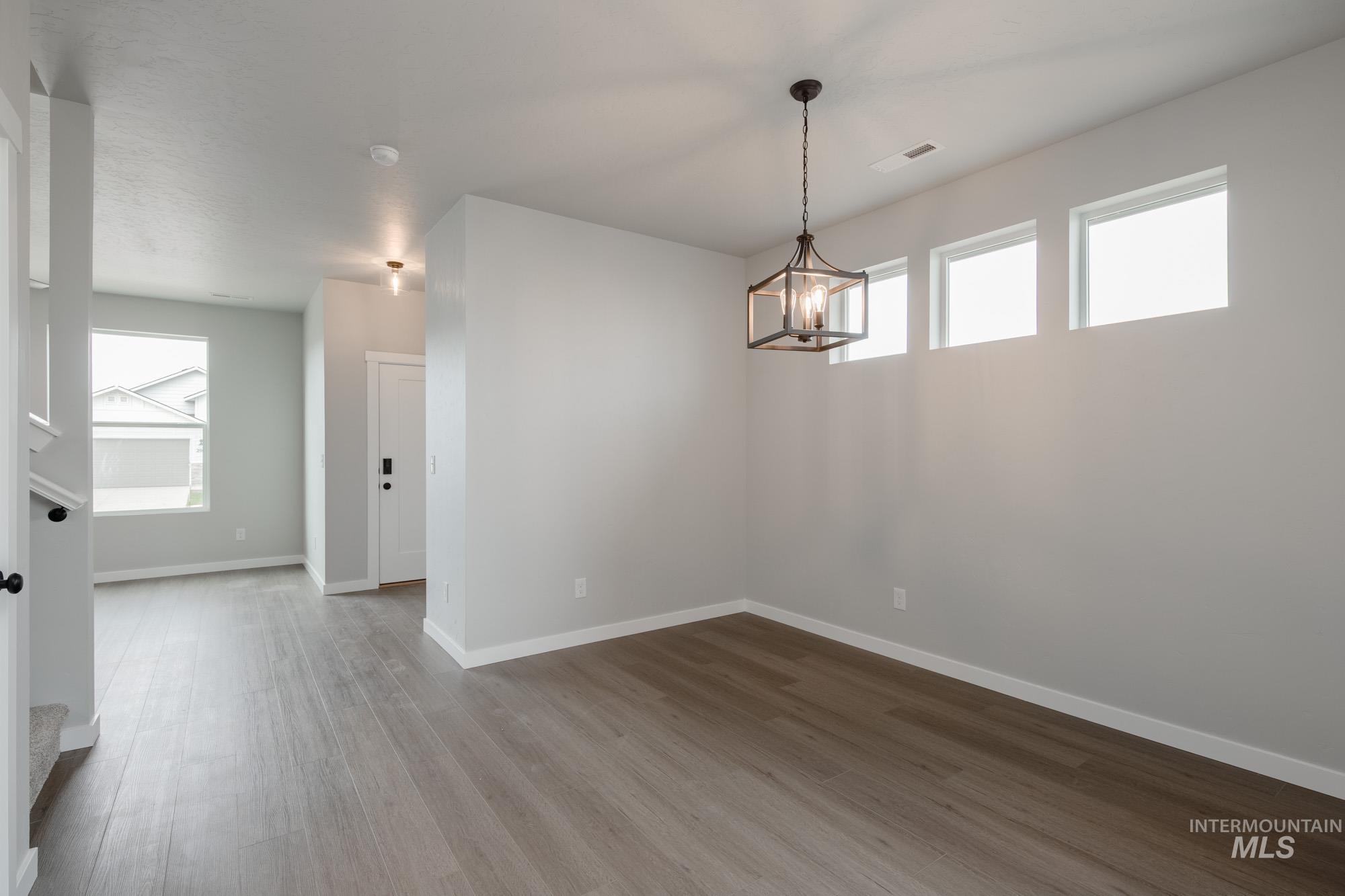 Unfurnished dining area featuring wood finished floors and a chandelier