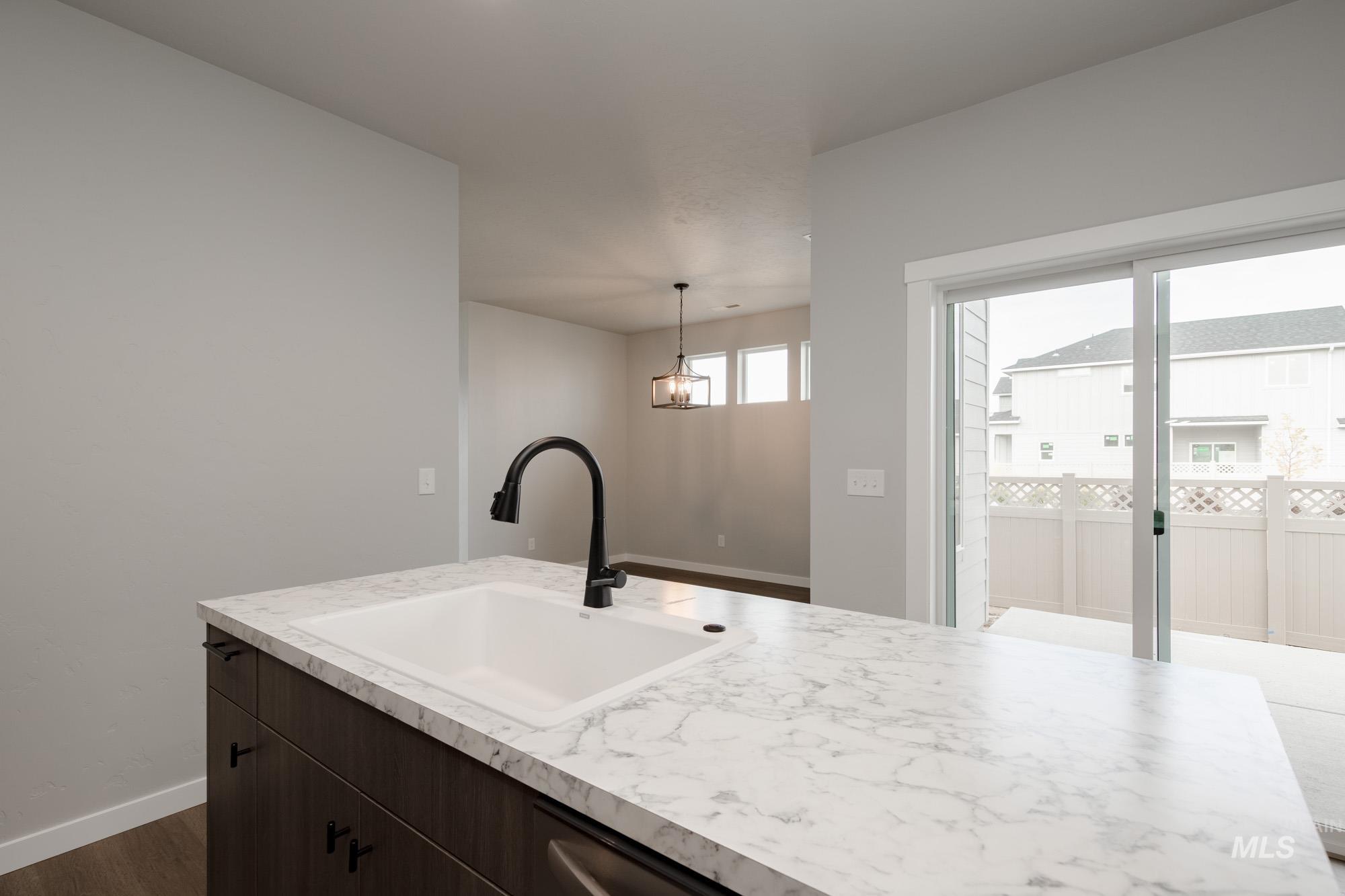 Kitchen featuring dark brown cabinets, light countertops, dark wood-style flooring, and decorative light fixtures
