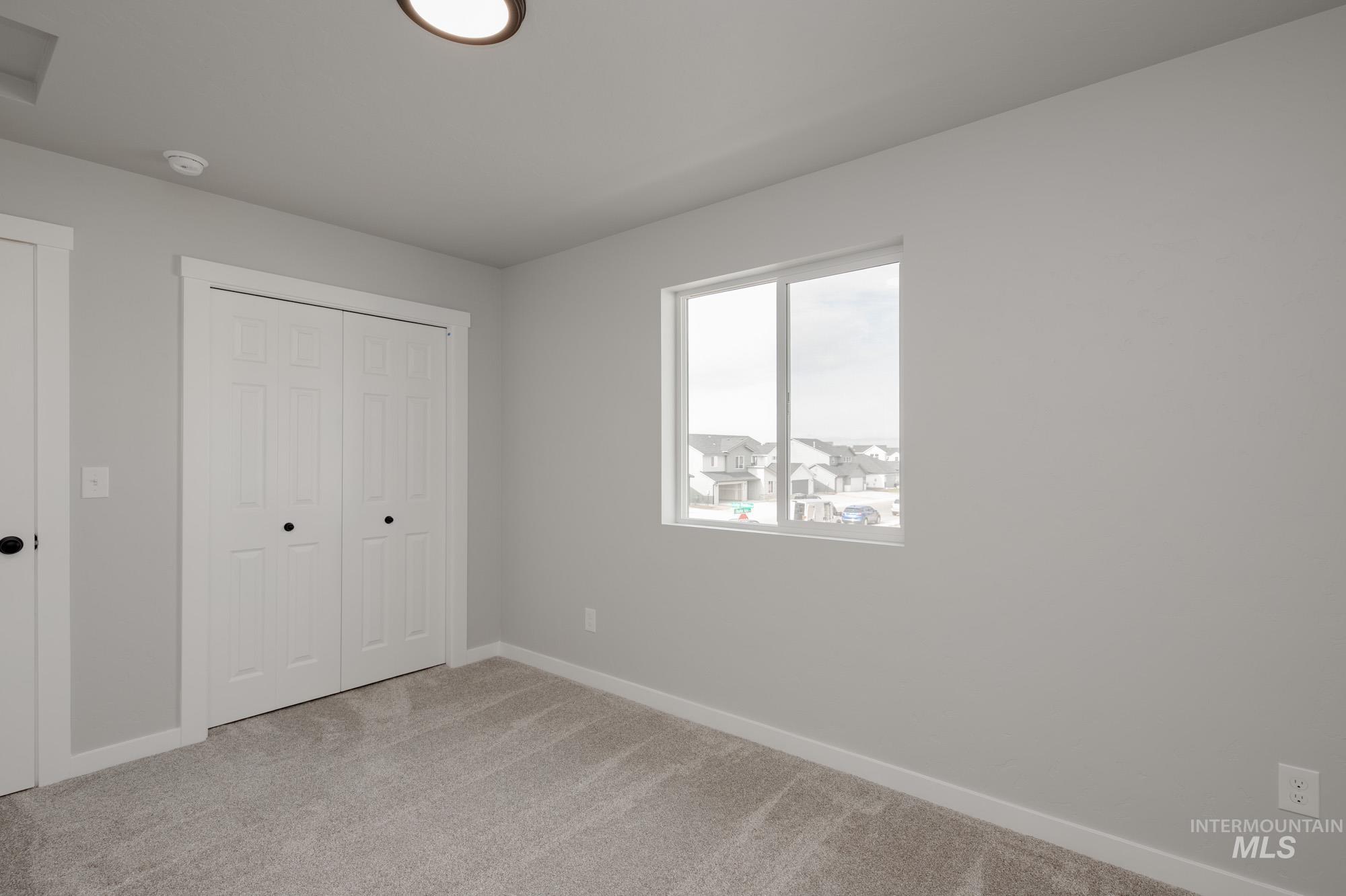 Unfurnished bedroom featuring light carpet and a closet
