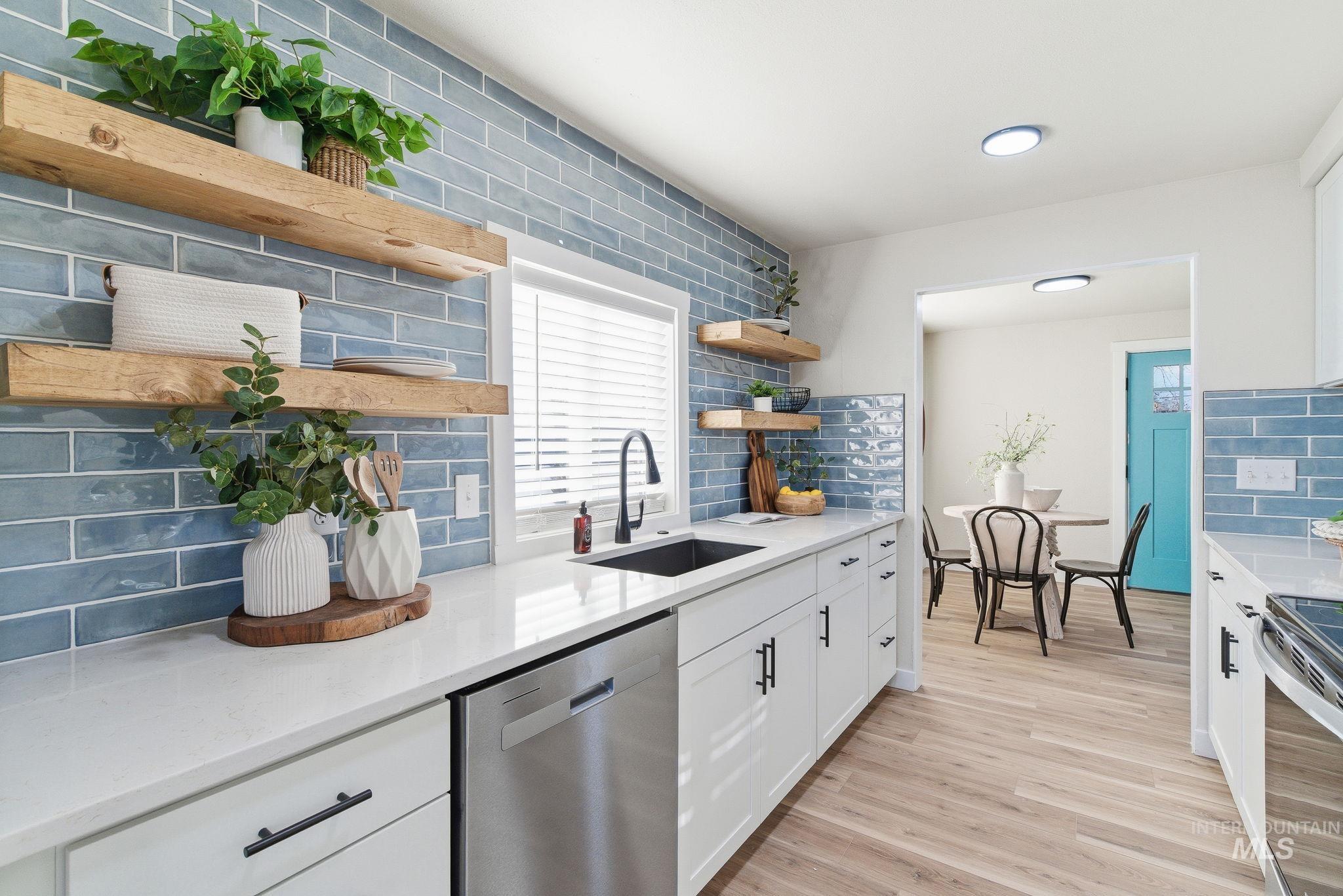 Kitchen featuring open shelves, white cabinets, appliances with stainless steel finishes, light stone countertops, and decorative backsplash