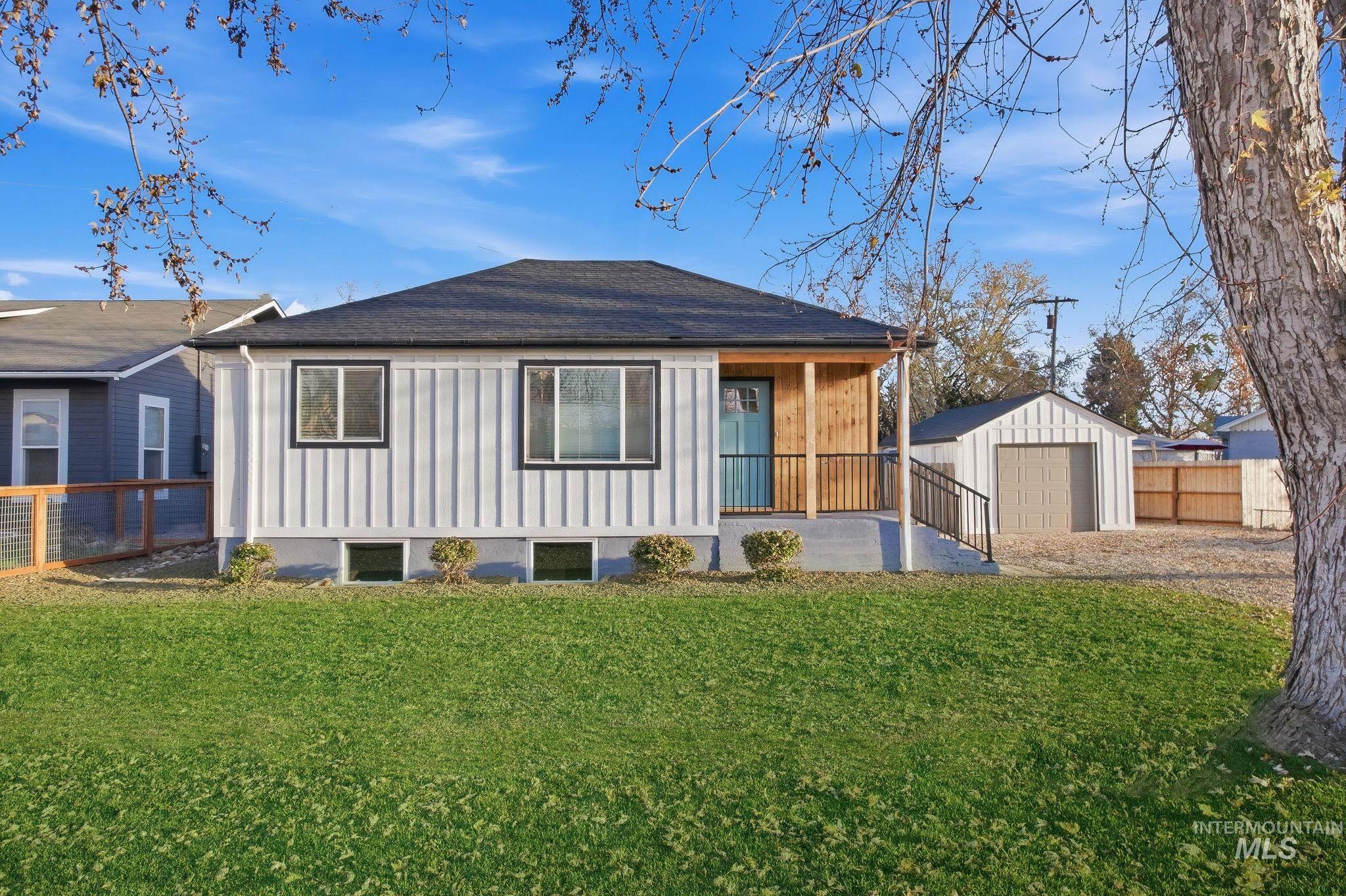 Rear view of house featuring an outbuilding, a porch, a detached garage, and board and batten siding