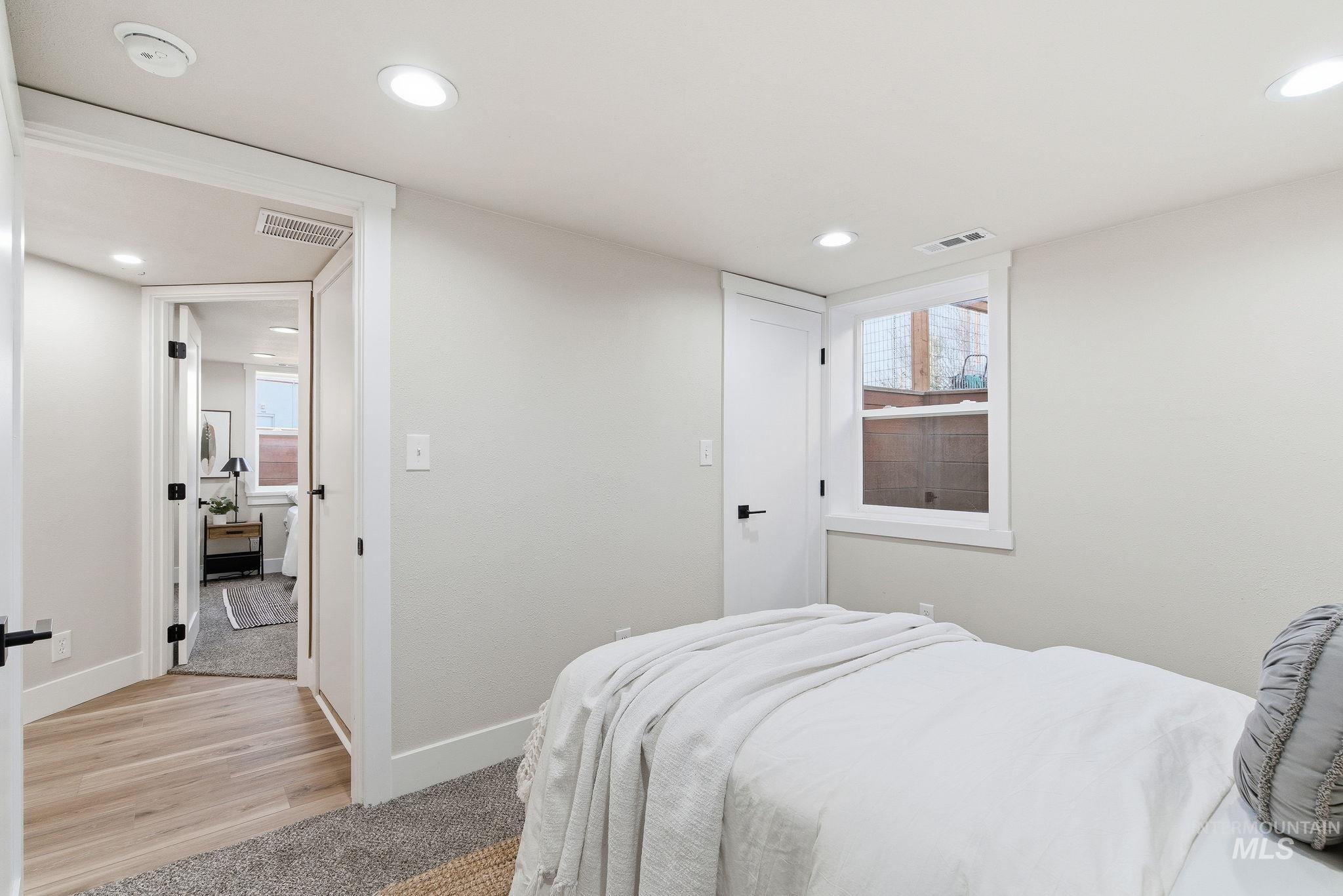 Bedroom with multiple windows, light colored carpet, and recessed lighting
