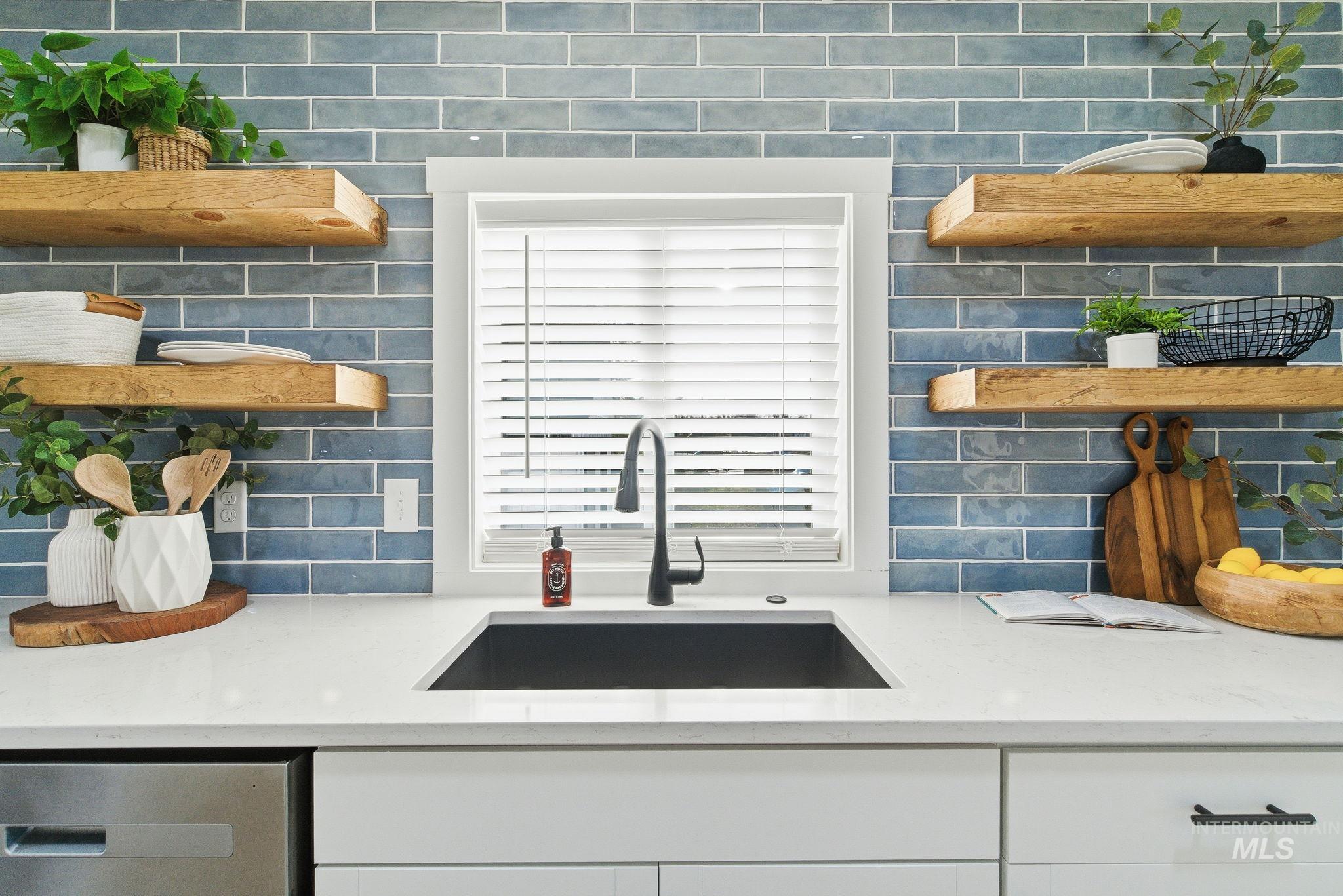 Kitchen with open shelves, light stone counters, white cabinets, and dishwasher