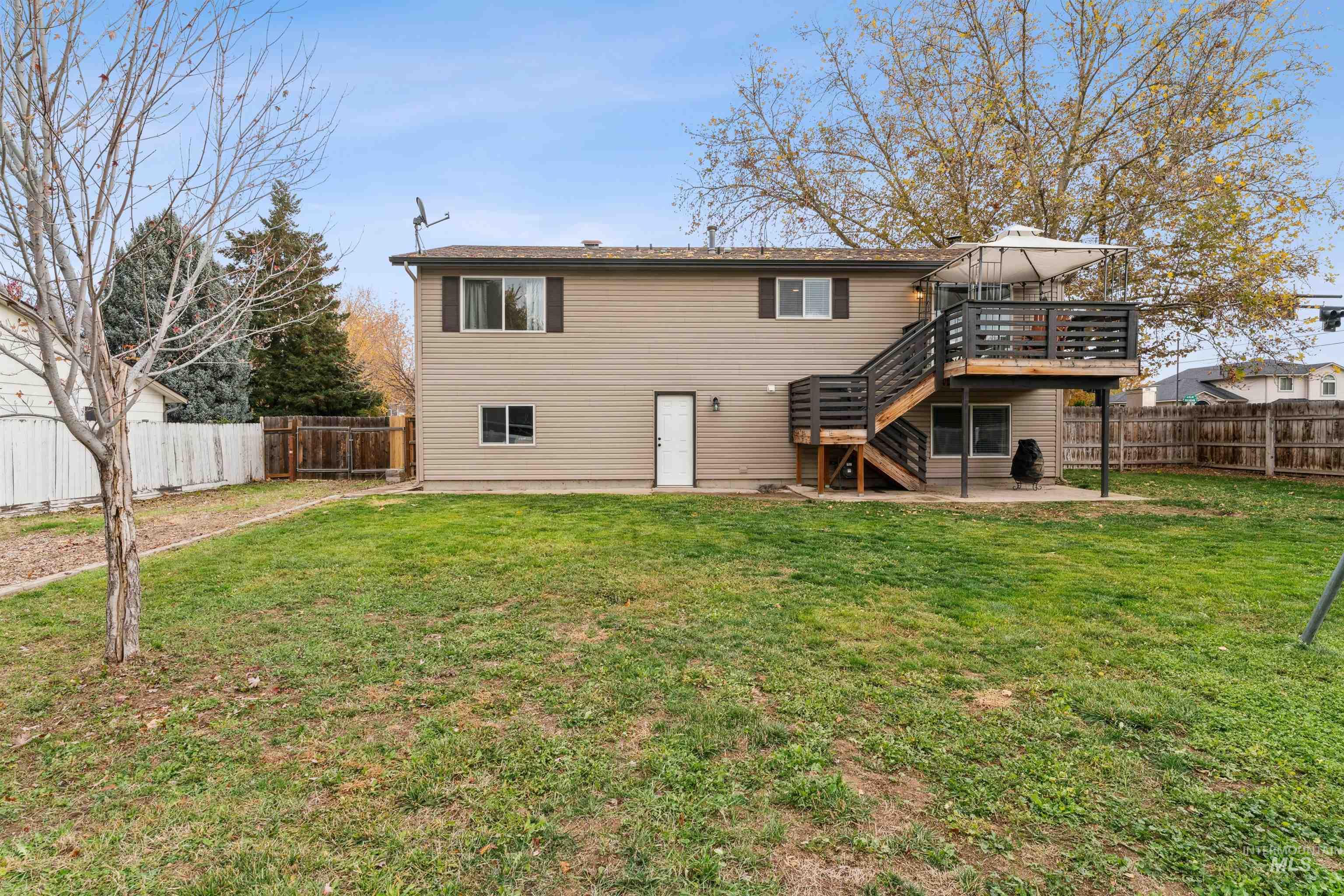 Back of house featuring stairs, a wooden deck, a fenced backyard, and a patio