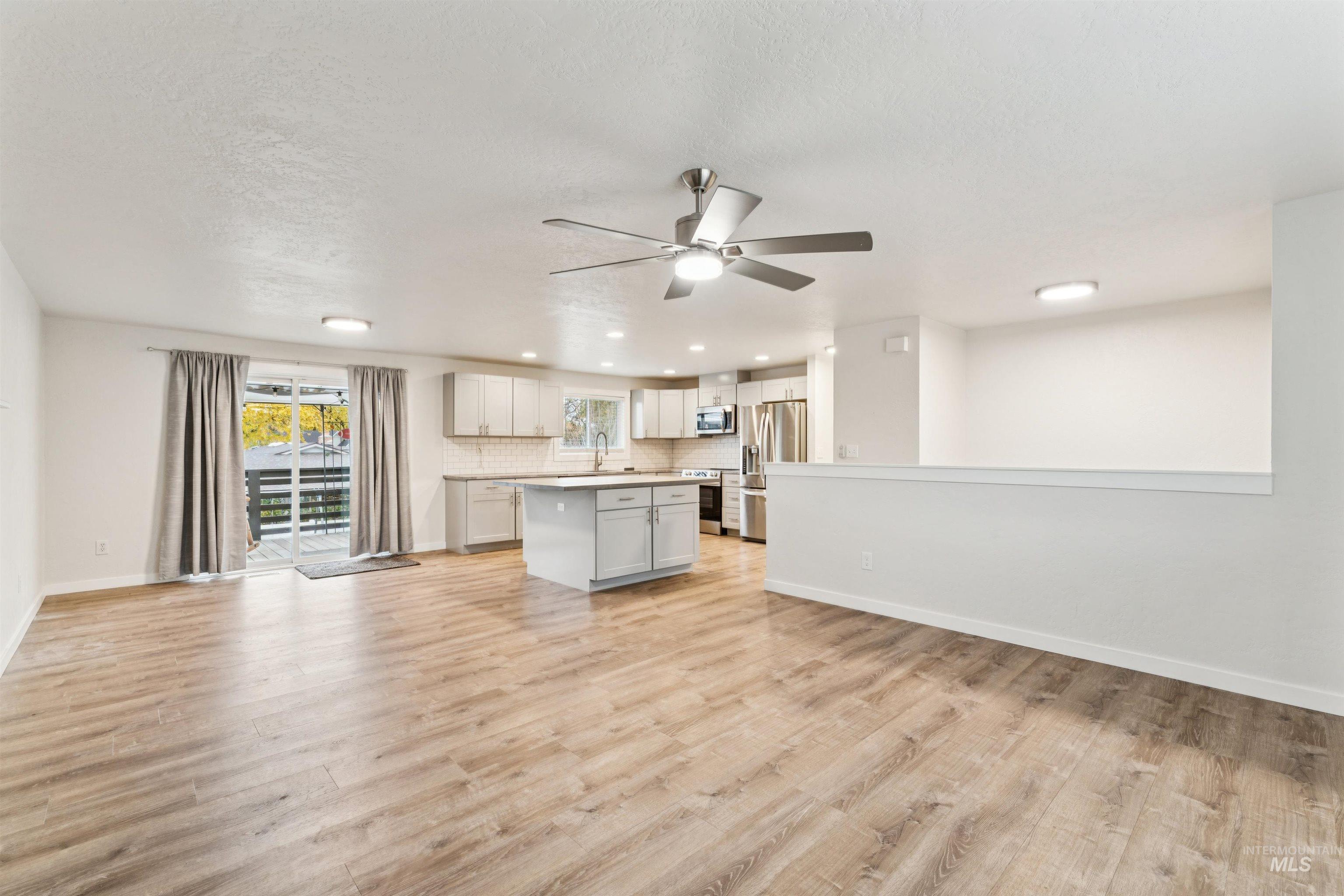 Kitchen with open floor plan, tasteful backsplash, light countertops, a center island, and light wood-style flooring