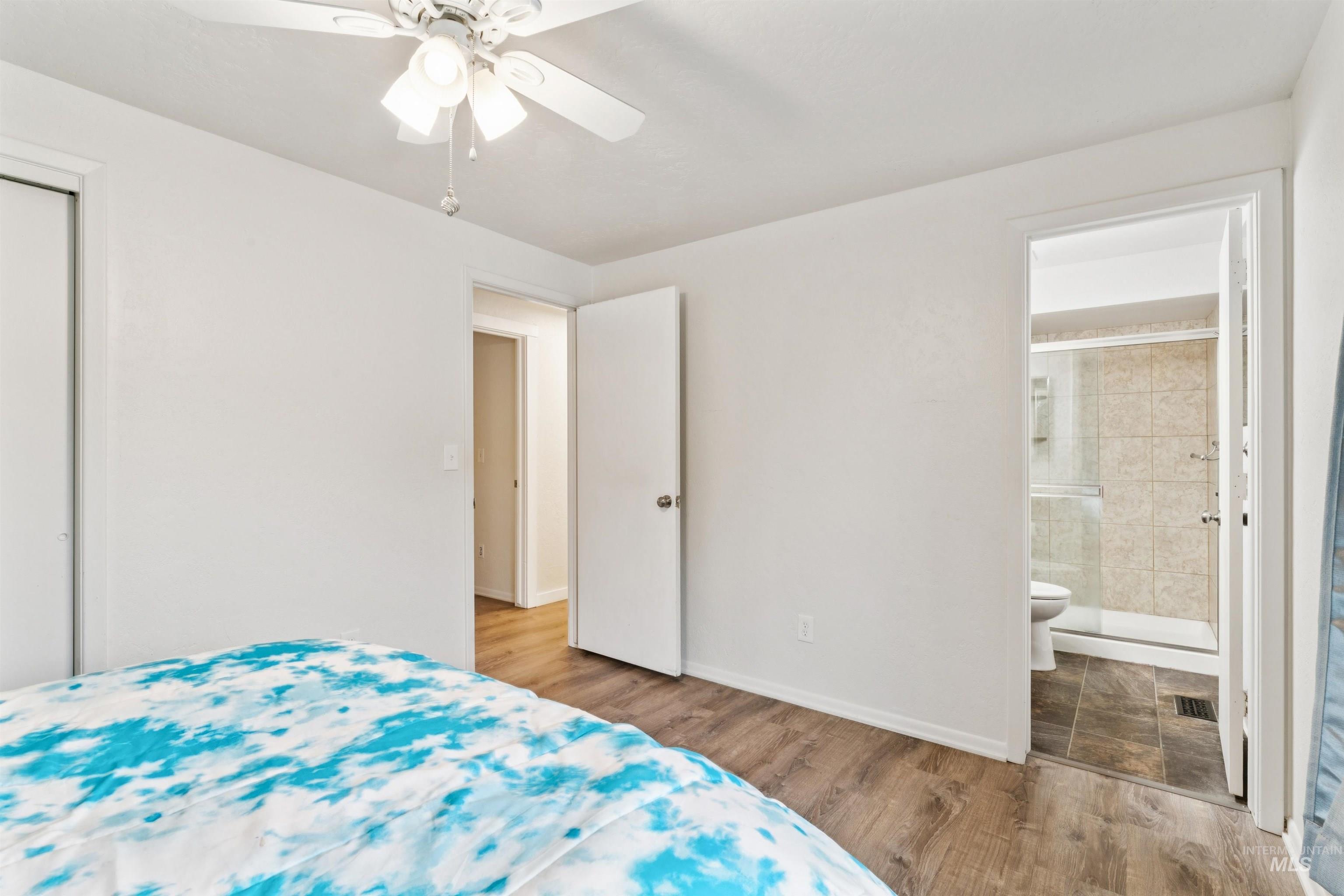 Bedroom with wood finished floors, ceiling fan, a closet, and connected bathroom