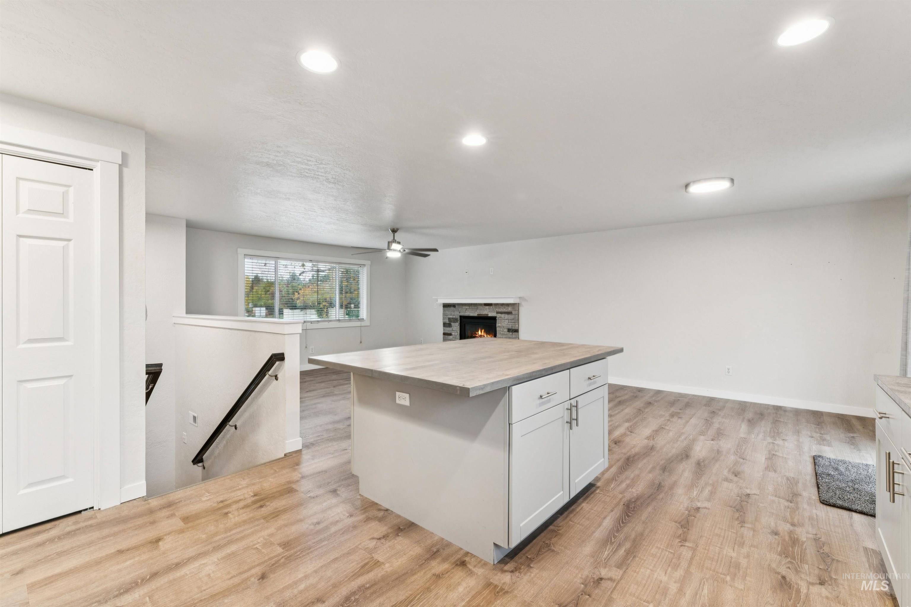 Kitchen with open floor plan, a center island, light wood-type flooring, recessed lighting, and a fireplace