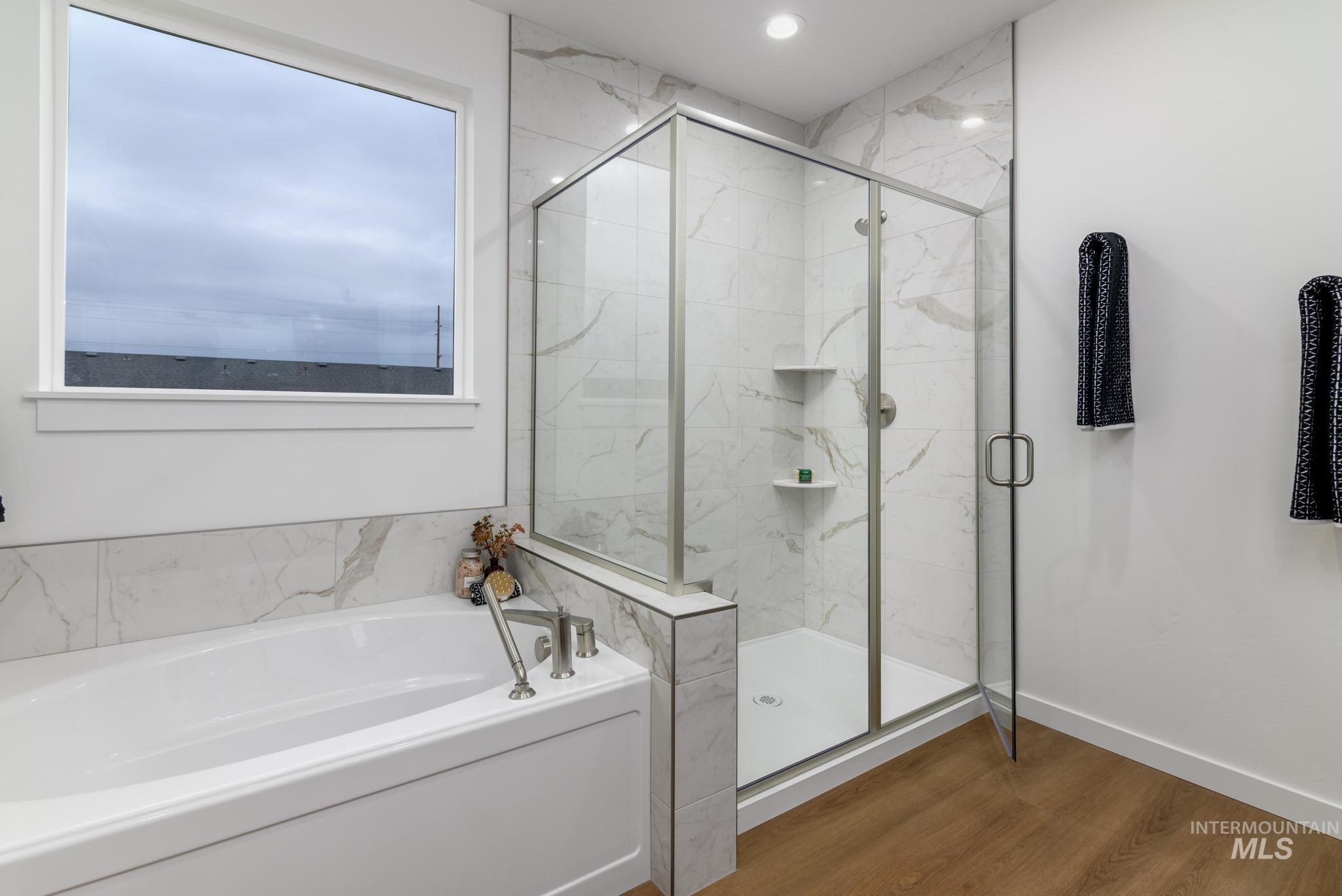 Full bath featuring a bath, dark wood finished floors, and a marble finish shower