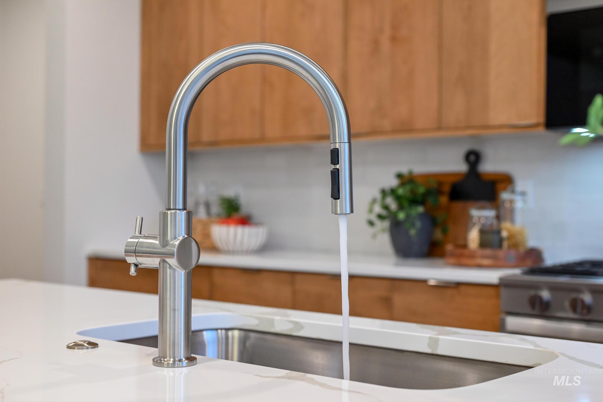 Kitchen view of brown cabinets, stainless steel range with gas cooktop, and black microwave