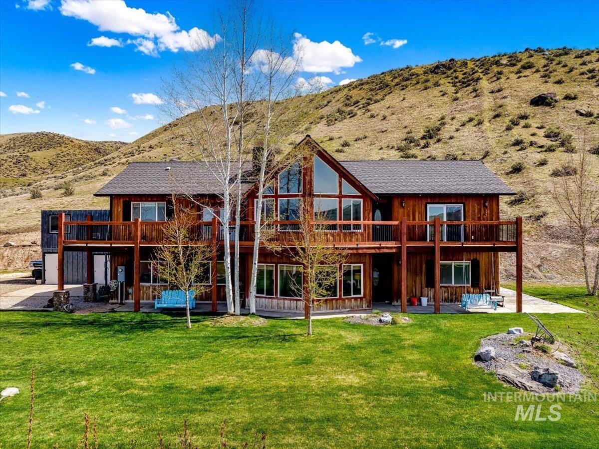 Back of house featuring a patio, a mountain view, a lawn, and a balcony