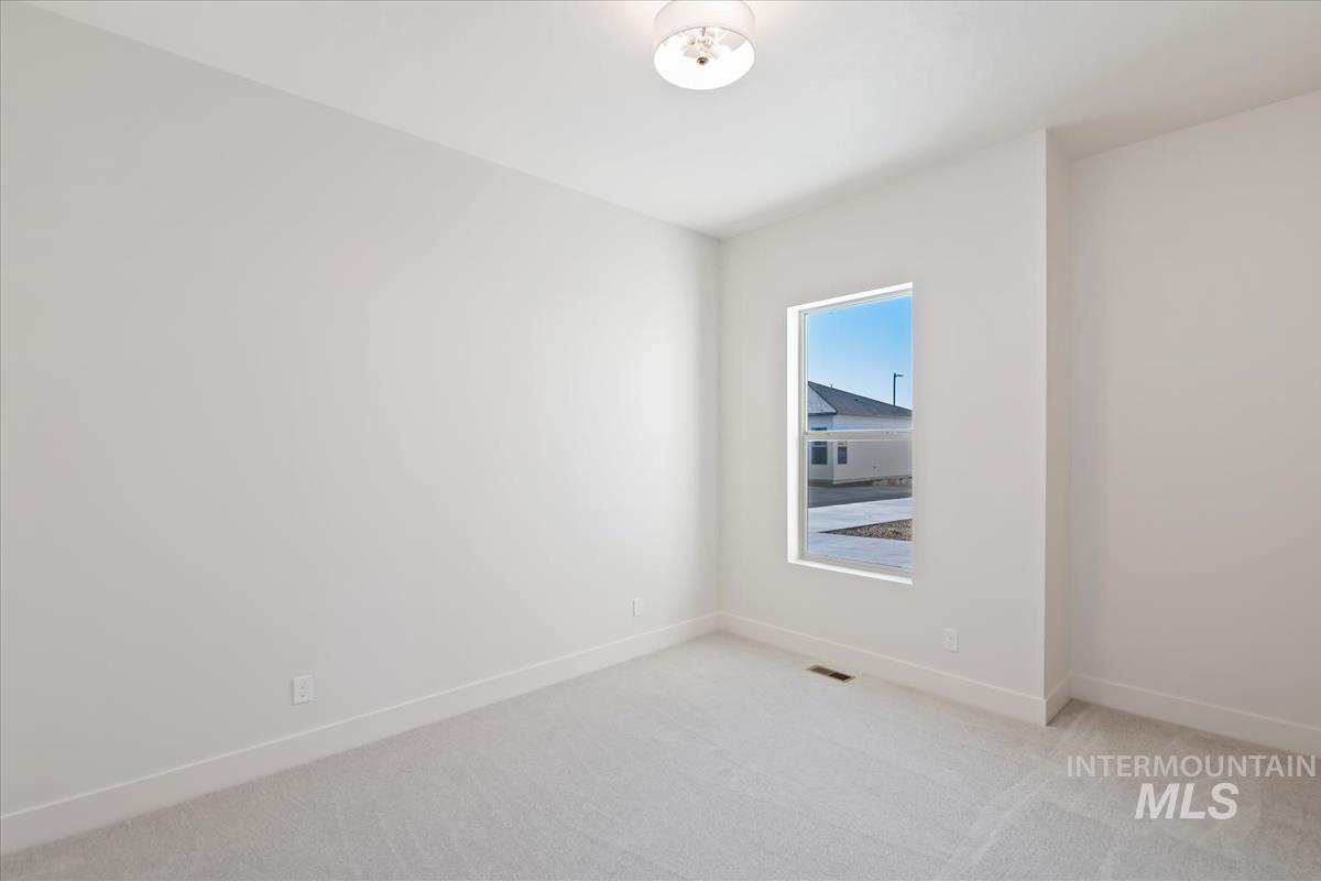 Spare room featuring light colored carpet and baseboards