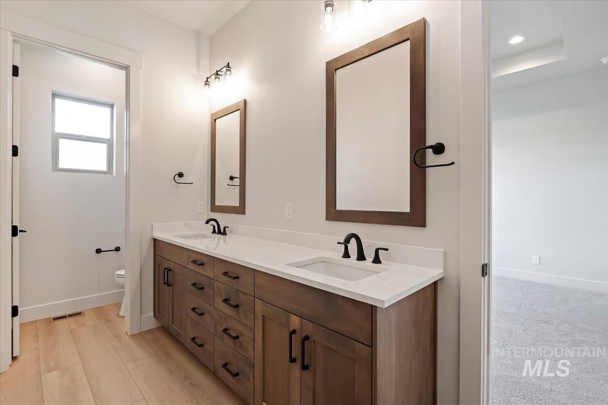 Bathroom featuring double vanity and light wood-type flooring