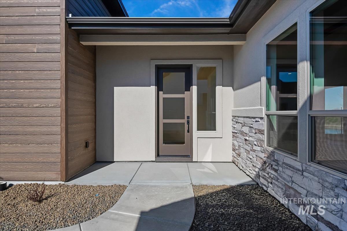 Entrance to property with stucco siding and stone siding