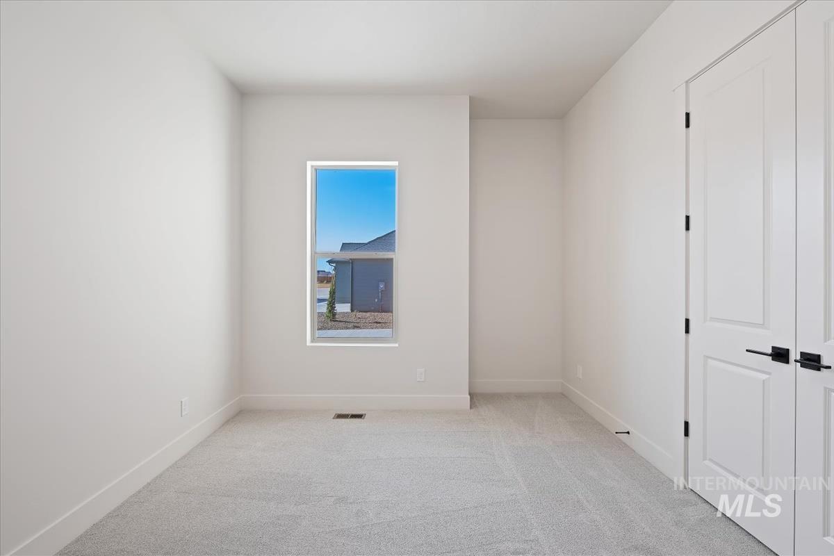 Unfurnished bedroom featuring light carpet and baseboards