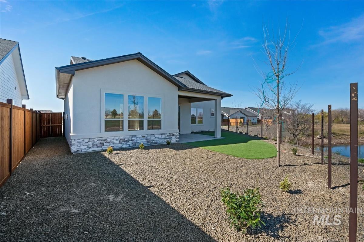 Rear view of property featuring a patio area, stone siding, stucco siding, and a fenced backyard