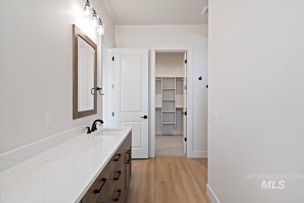 Bathroom with vanity, light wood finished floors, and a spacious closet