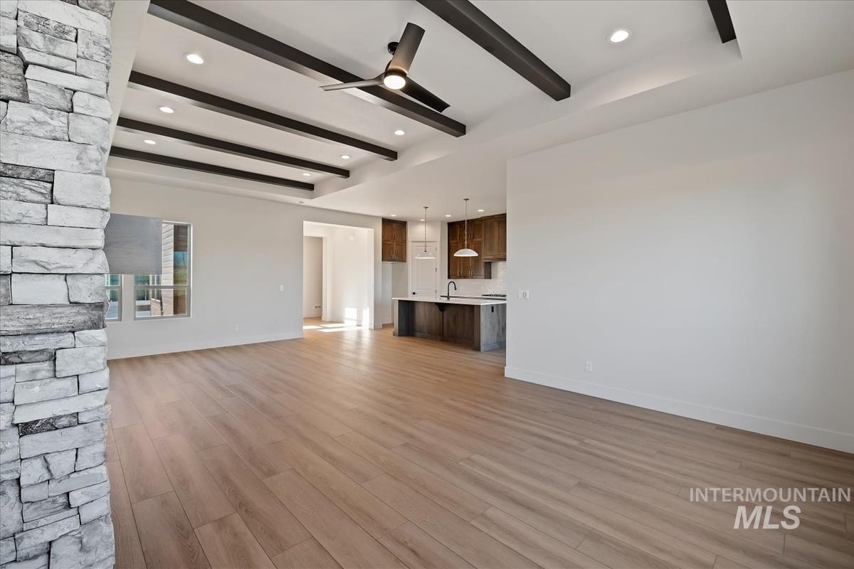 Unfurnished living room featuring beamed ceiling, light wood-style floors, ceiling fan, and recessed lighting