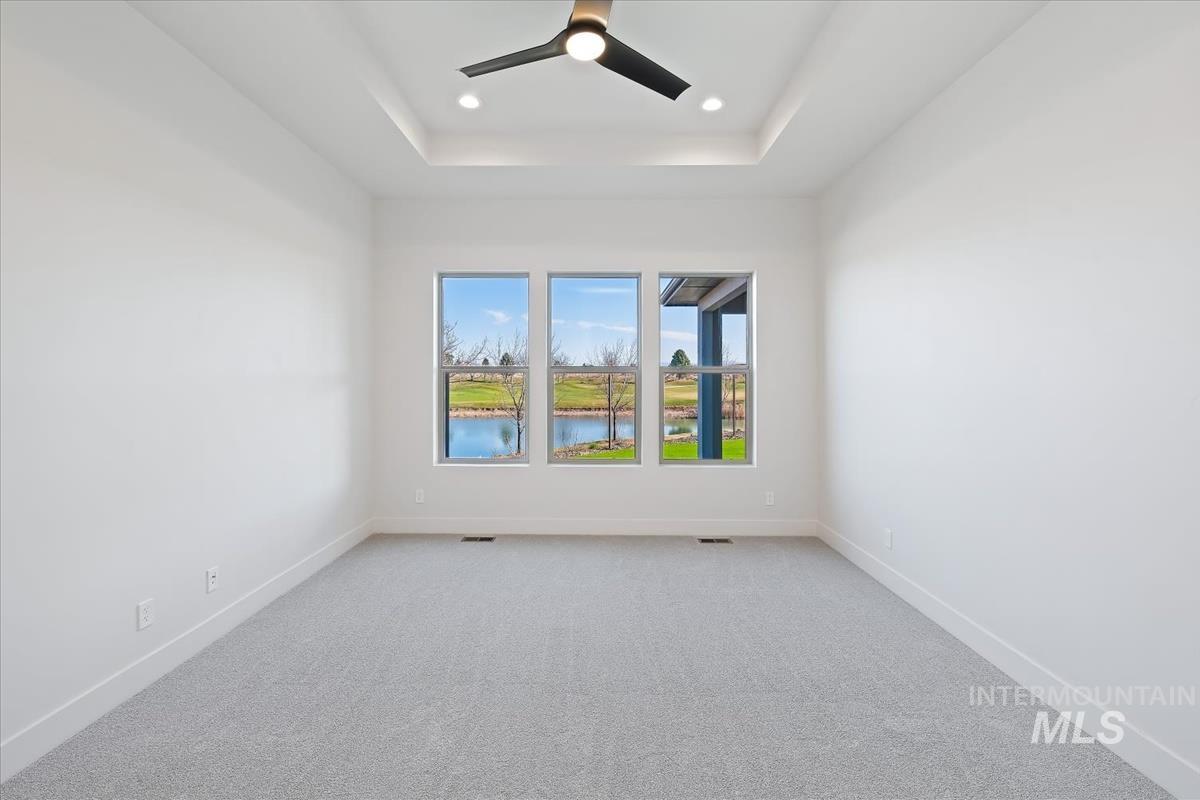 Carpeted empty room featuring ceiling fan, a water view, and recessed lighting
