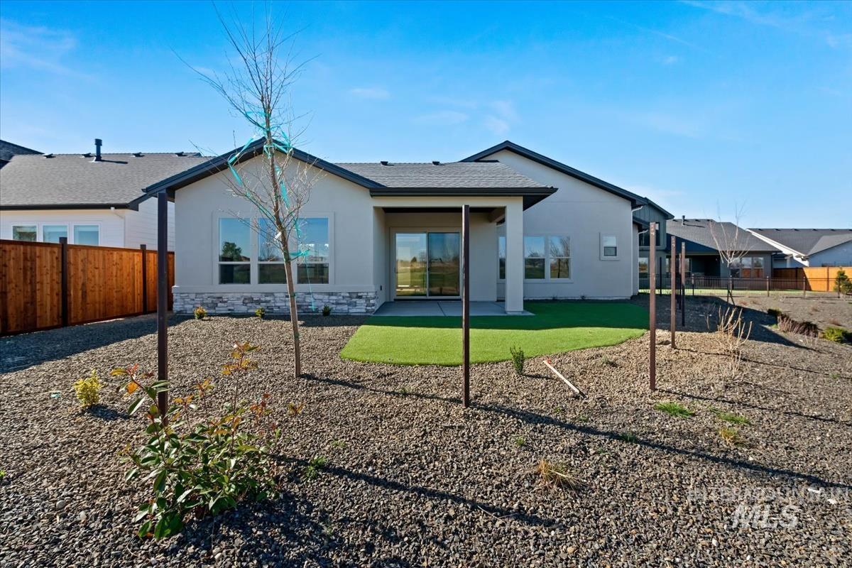 Rear view of property featuring a patio, a fenced backyard, stucco siding, stone siding, and roof with shingles