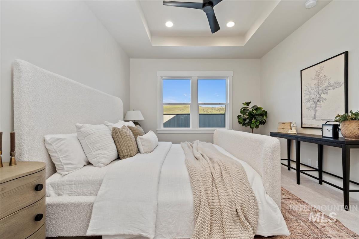 Bedroom with a tray ceiling, light carpet, ceiling fan, and recessed lighting