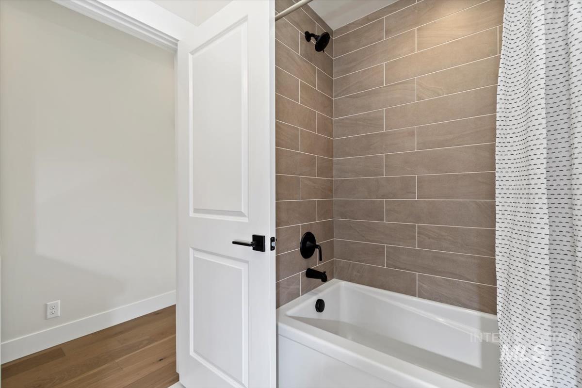 Full bathroom featuring shower / bath combination with curtain and wood finished floors