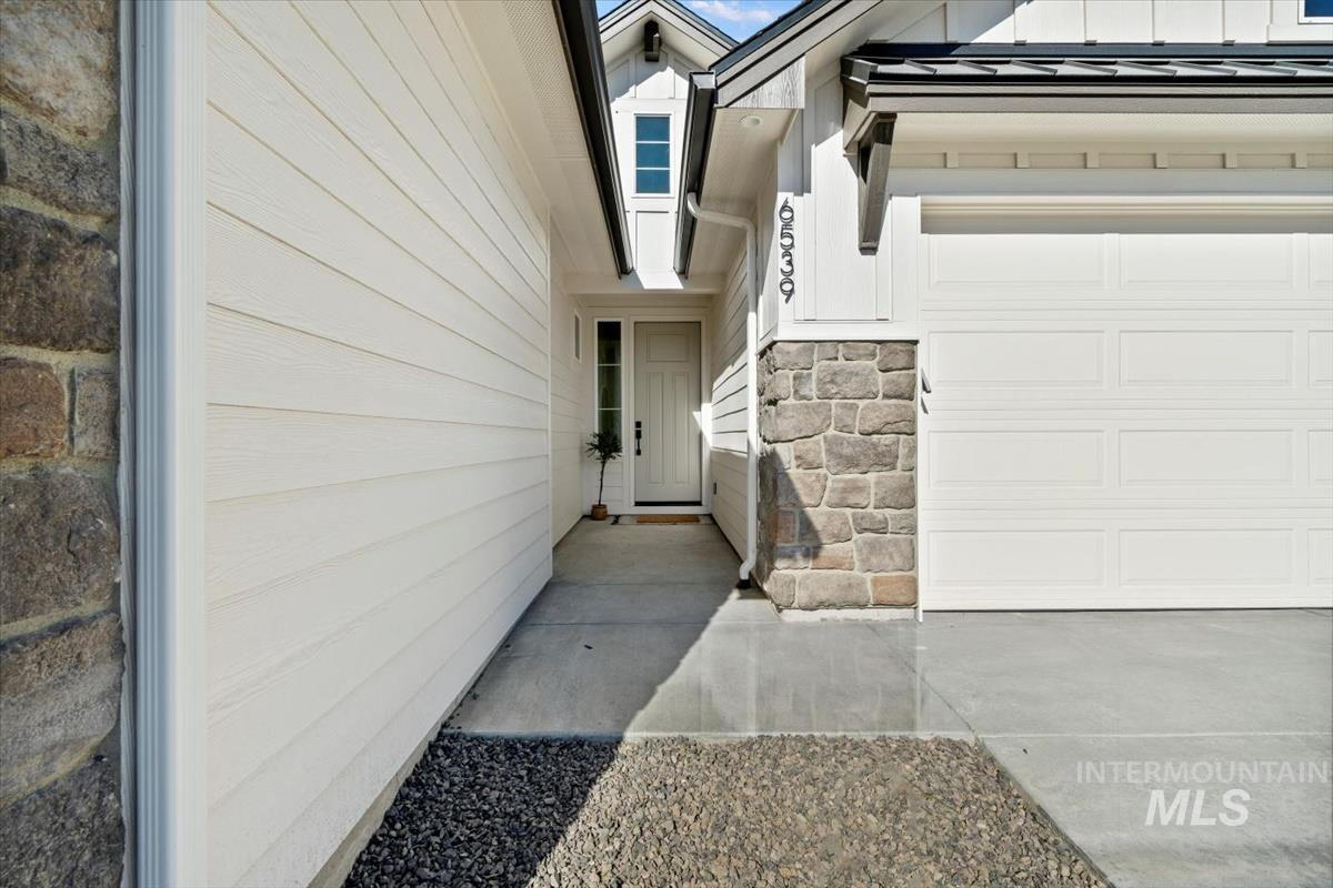 Entrance to property with stone siding, a garage, and board and batten siding