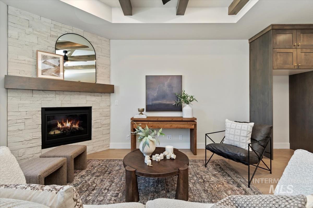 Living room with a fireplace, light wood-type flooring, and beam ceiling