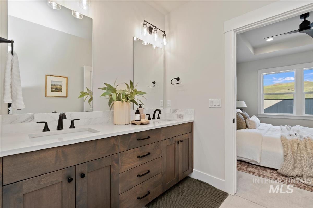 Ensuite bathroom featuring double vanity and baseboards