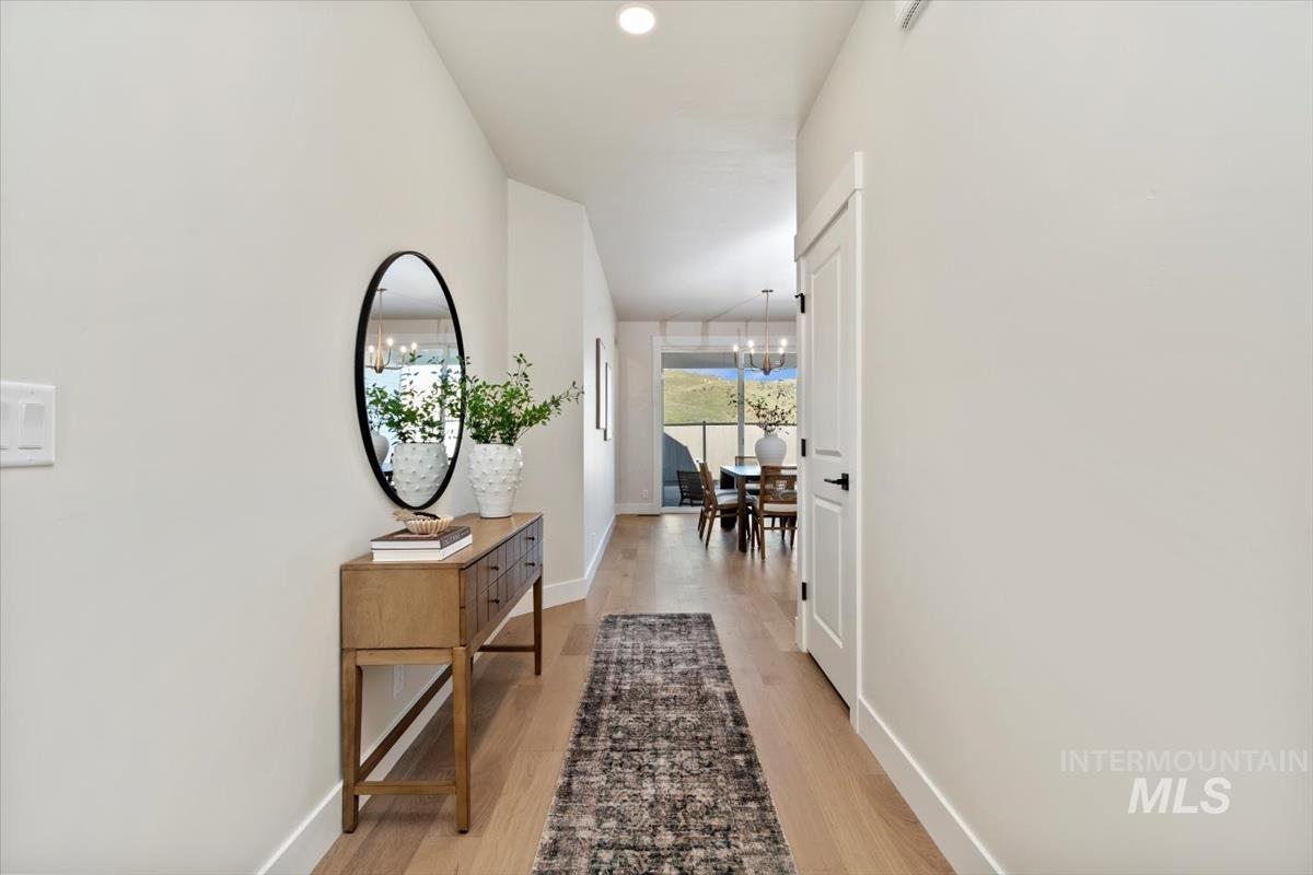 Hall with light wood finished floors, recessed lighting, and a chandelier