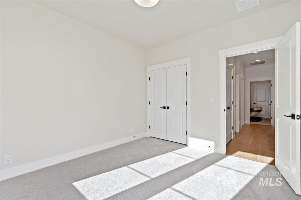 Unfurnished bedroom with light carpet and a closet
