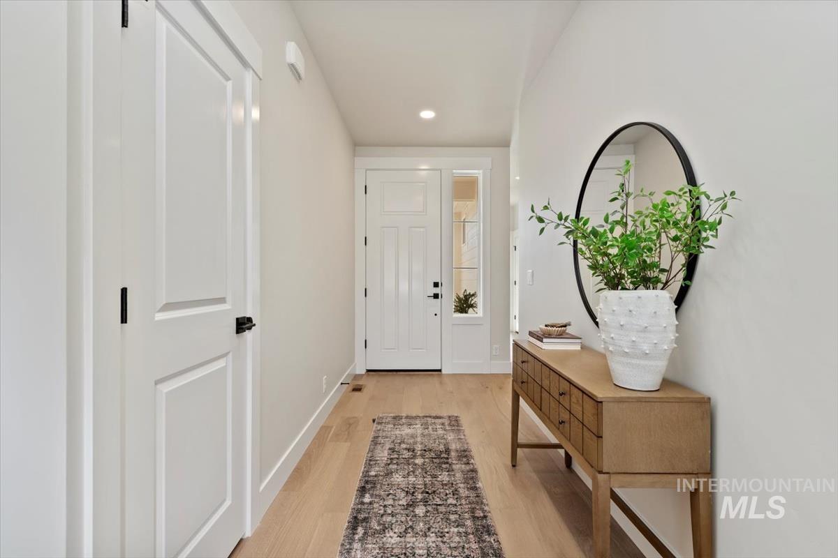 Doorway to outside with light wood finished floors and recessed lighting