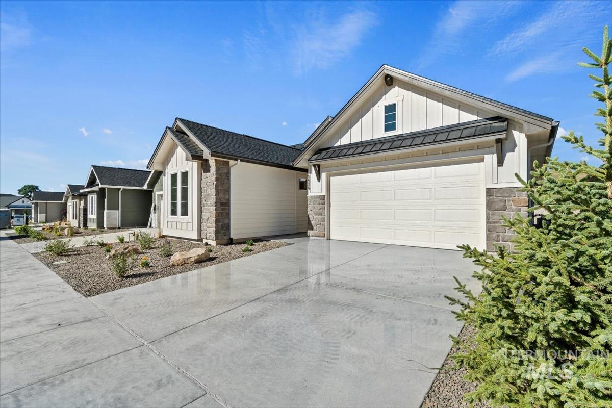 View of home's exterior featuring stone siding, board and batten siding, driveway, and a standing seam roof