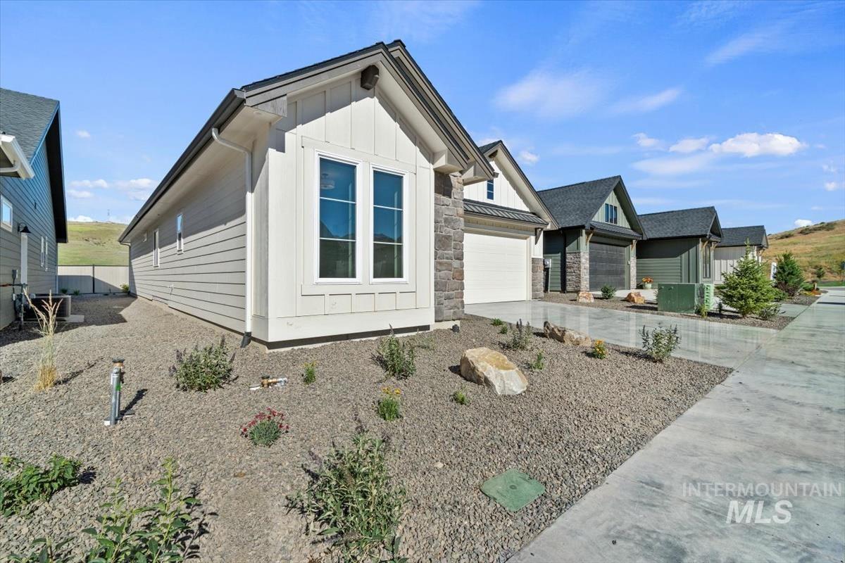 View of home's exterior with board and batten siding, concrete driveway, stone siding, and a garage